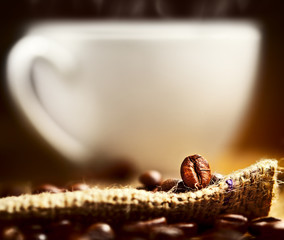 Coffee beans and cup on background