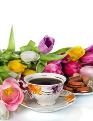 Bouquet of colorful tulips and  tea cup full of tea isolated on