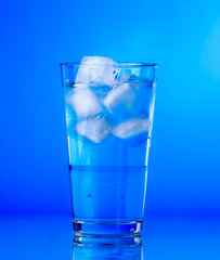 Glass of water on blue background. water with ice in glass