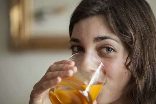 Young Woman with Beautiful Green Eyes Drinking Mango Juice
