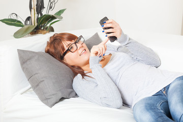 Beautiful Young Woman with Smartphone on the Sofa