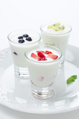 three yogurt with fruit in a glass beaker vertical closeup