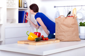 unpacked groceries and a woman at the cookbooks