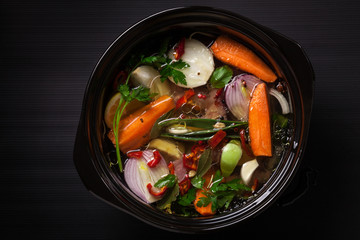Fresh vegetable soup in a pot on black background
