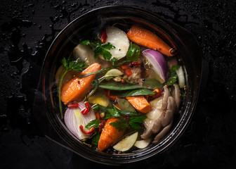 Fresh vegetable soup in a pot on black background