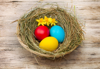 Basket with nest, colored eggs and flowers