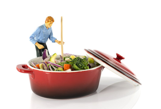 man stirring vegetarian food in red saucepan