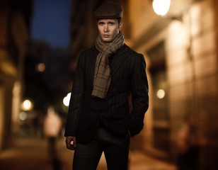 Young man in brown jacket wearing cap and scarf 
