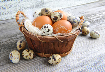 Different types of eggs in a basket on a old wooden background