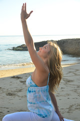 Young woman doing yoga at the beach