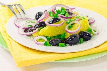 Orange salad with olives, tomatoes and onions on a plate