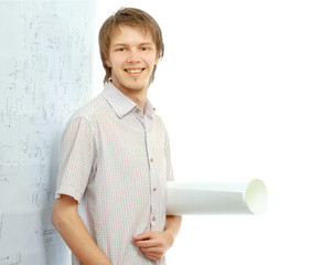 A young man near a diagram, holding a rolled draft