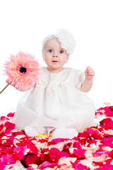 cute baby girl with flower sitting among rose petals