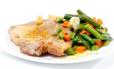 Fried pork meat with vegetables on white plate.