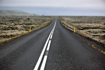 Highway through Iceland landscape at foggy day