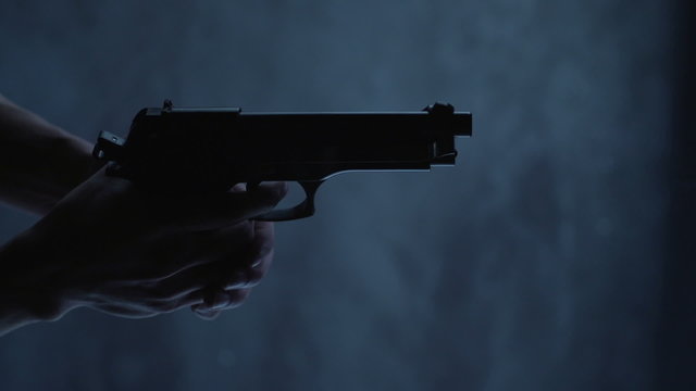 Man with 9 mm handgun takes a shot. Shot from above