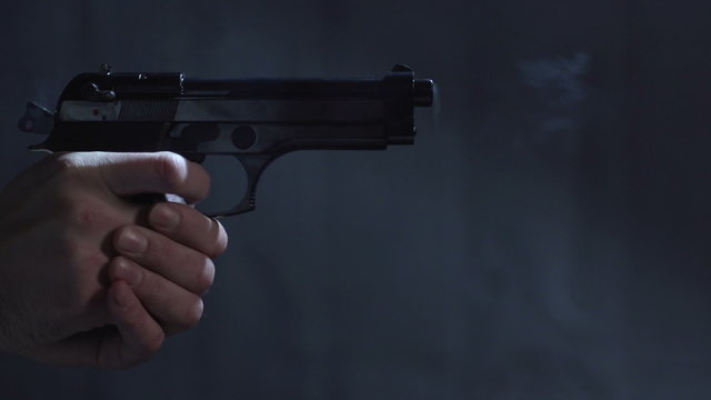 Close profile of man holding a 9 mm handgun takes three shots