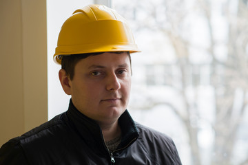 Worker in a helmet on a background window