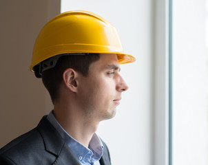 Worker in a helmet on a background window