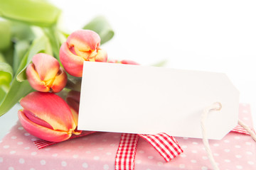 Bouquet of beautiful tulips next to a gift with an empty card