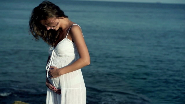 Pregnant woman standing on the seashore, slow motion shot at 240