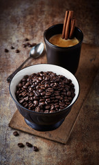 Dark roasted coffee beans and a mug of coffee