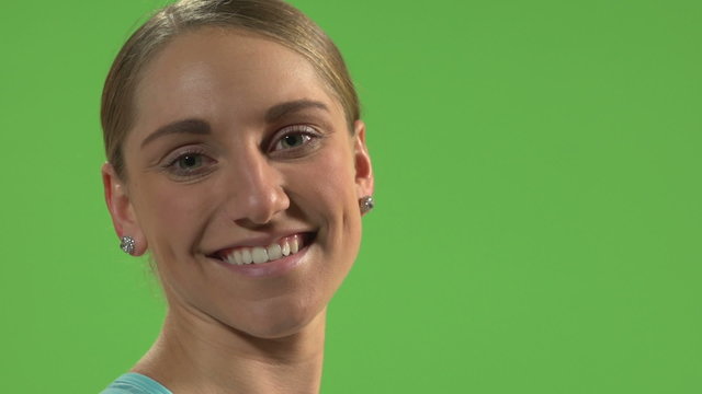 Young woman smiling in front of green screen.