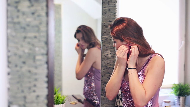 Beautiful Woman Putting On Earrings In Bathroom