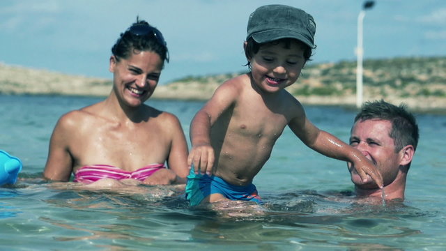 Happy family having fun in the sea, slow motion shot at 240fps