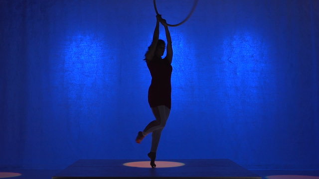 Aerial hoop performer, blue background, spinning silhouette