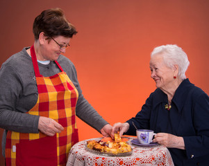 Mother and daughter having tea with apple pie