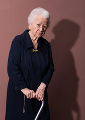 Old woman with a cane on brown background