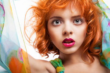 Girl with red hair and colorful dress over white