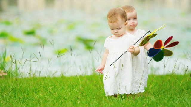 Caucasian girl twins toddling together in garden