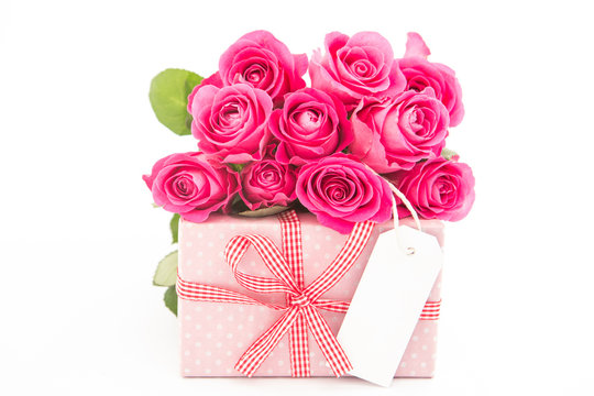 Bouquet of beautiful pink roses next to a pink gift with an empt