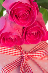 Pink roses resting on pink polka dot wrapped present