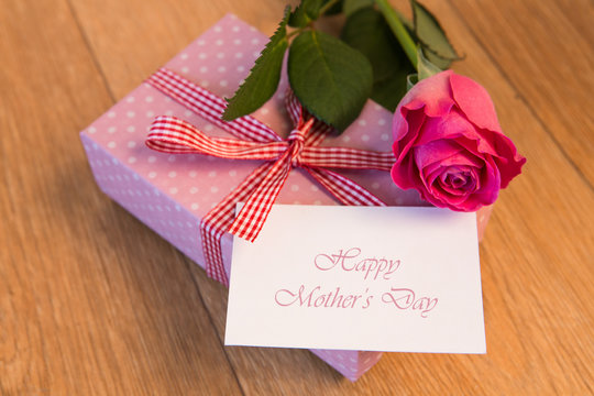 Pink wrapped present with happy mothers day card and pink rose