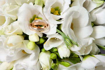 wedding rings on beautiful bouquet of white freesias