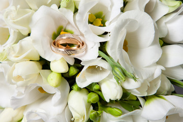Obraz premium wedding rings on beautiful bouquet of white freesias