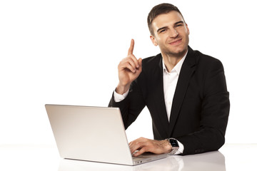 attractive businessman shows his finger up behind his laptop