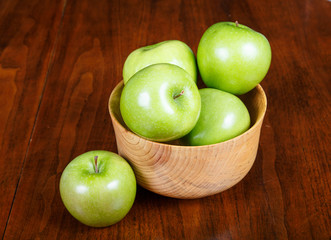 Bowl of Green Apples with One on Table