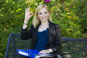 Junge blonde Frau gibt Handzeichen auf Parkbank