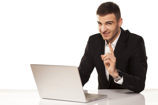 attractive businessman shows his finger up behind his laptop