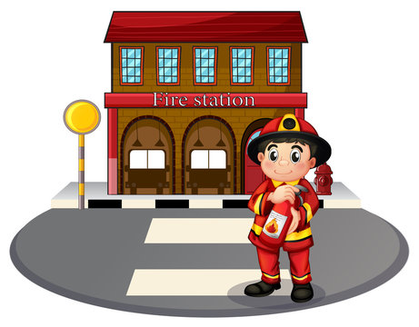 A fireman holding a fire extinguisher in front of the fire stati