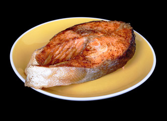 Salmon steak on plate. Isolated on black