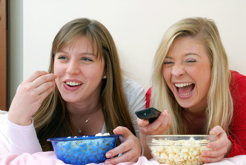 Dos amigas disfrutando y comiendo palomitas de maíz.viendo tv