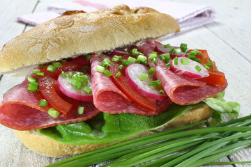 Sandwich with salami, tomato, lettuce and radish