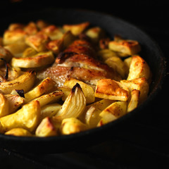 Frying pan with roasted chicken, vegetables, herbs and spices
