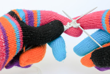 Knitting hands in colorful gloves