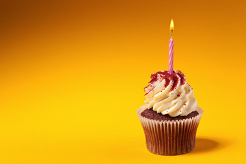 chocolate cupcake with candle isolated on orange background with